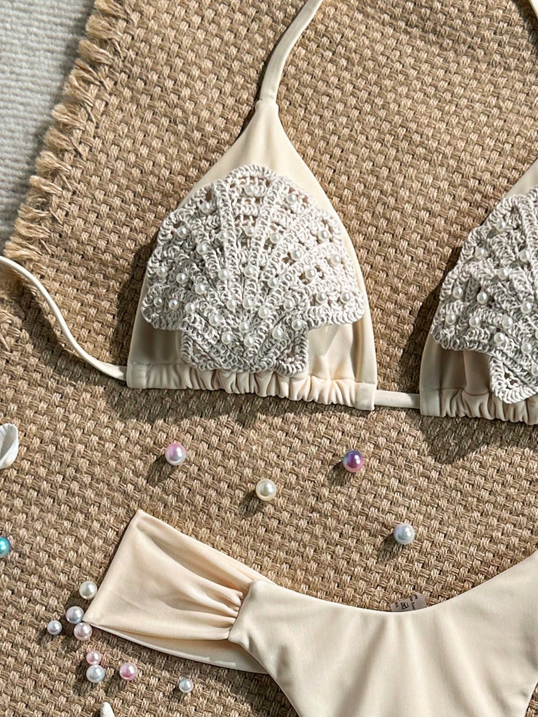 Women's 2-piece triangle cup bikini set in solid color featuring woven pearl shell decoration, halter neckline, and high-waist side-tie ruched bottoms.