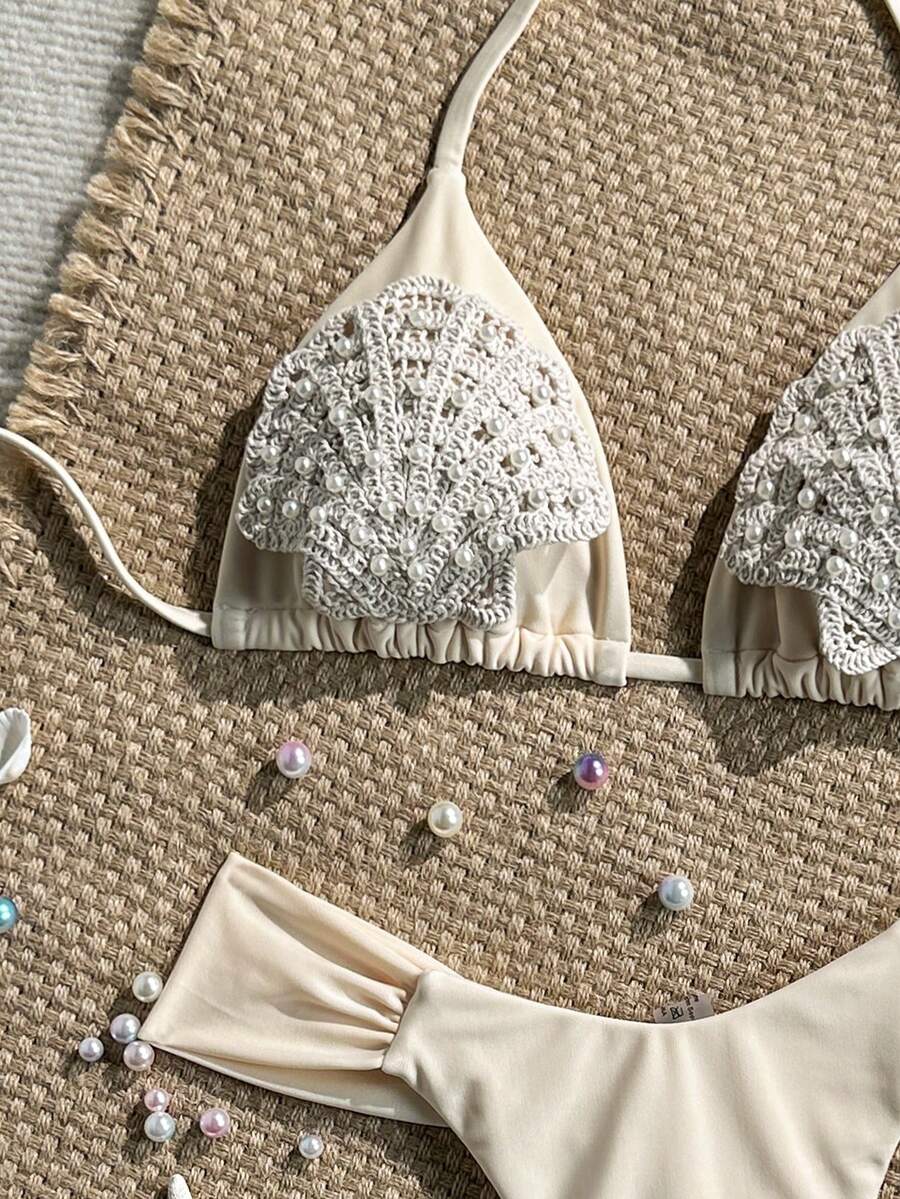 Women's 2-piece triangle cup bikini set in solid color featuring woven pearl shell decoration, halter neckline, and high-waist side-tie ruched bottoms.