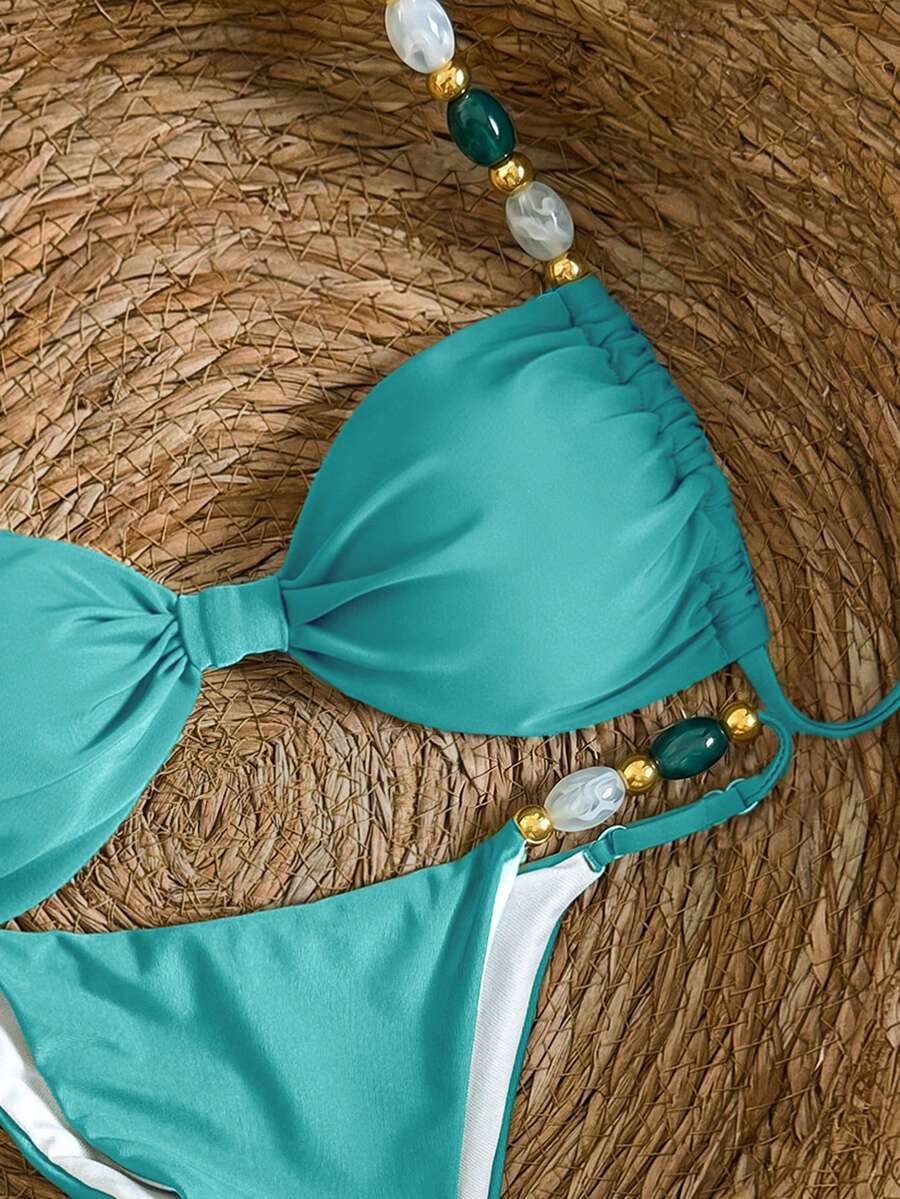Women's green halter neck bikini set featuring color-block beaded shoulder straps, back tie detail, and high cut bottoms.