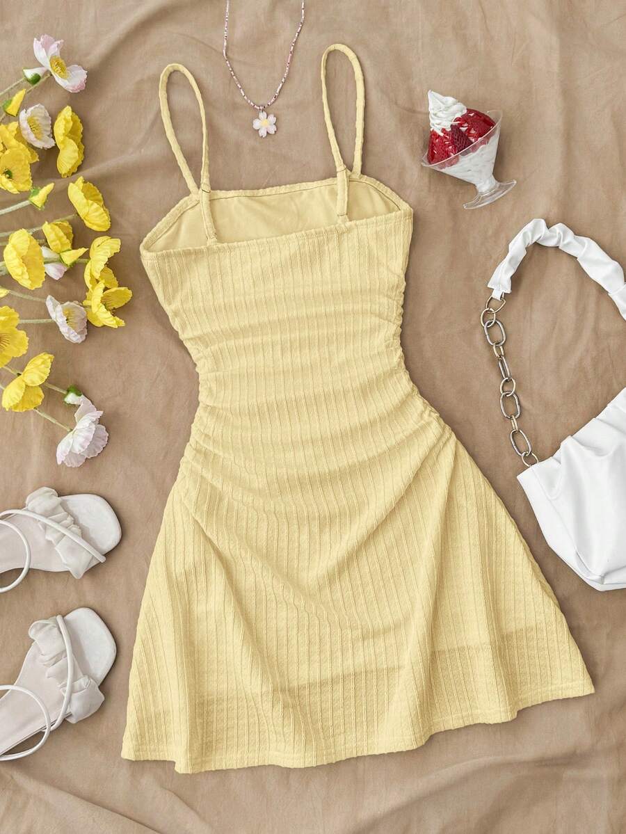 Tween girl yellow mini sundress with large pink floral hibiscus print, spaghetti straps, high waist, flared hem, and sleeveless cami style for summer beach wear
