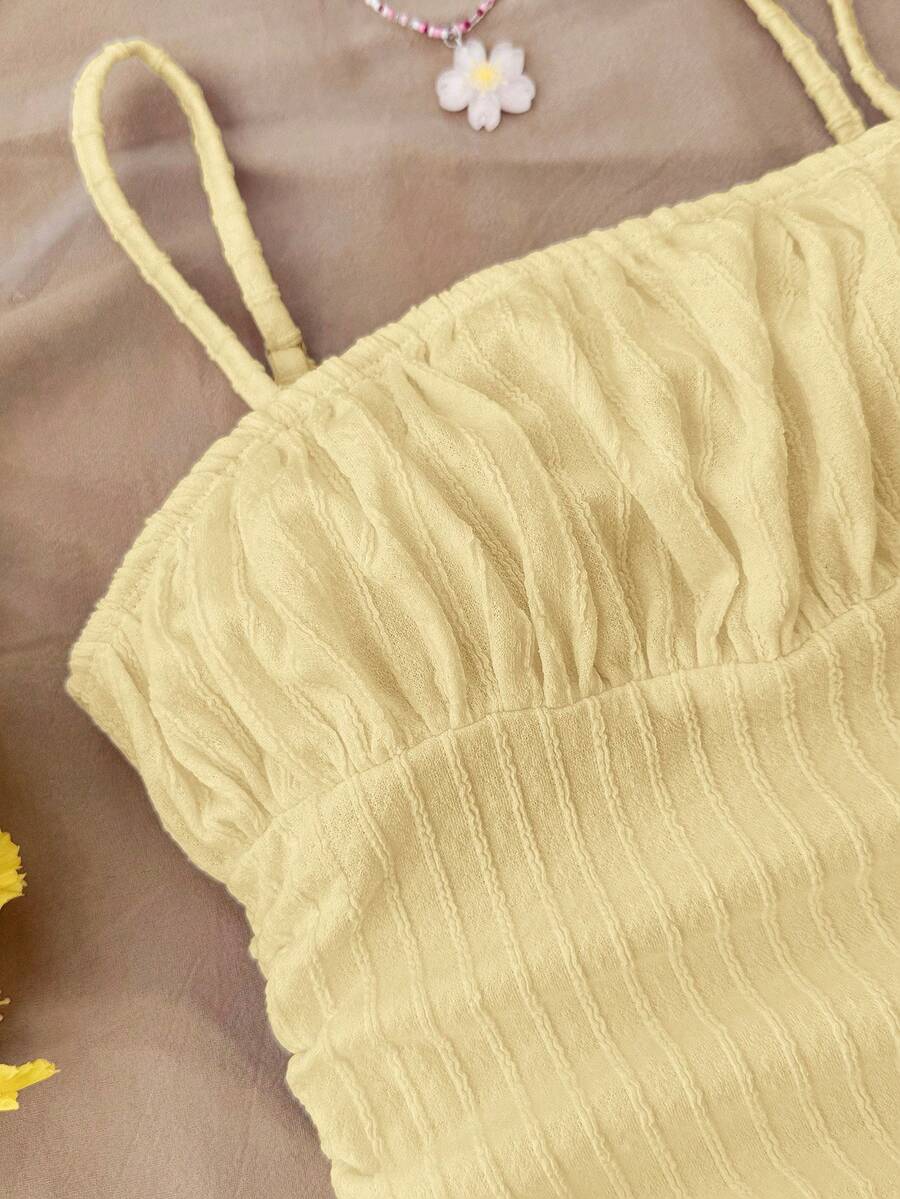 Tween girl yellow mini sundress with large pink floral hibiscus print, spaghetti straps, high waist, flared hem, and sleeveless cami style for summer beach wear