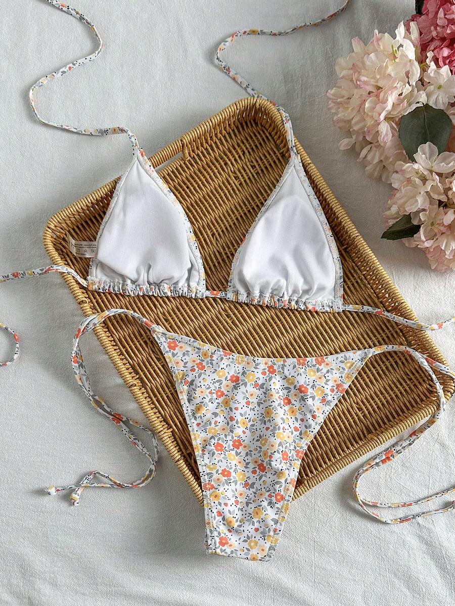 Women's black two-piece bikini set featuring a halter neck with a colorful sun pendant, triangle cups, and high-cut tie-side bottoms.