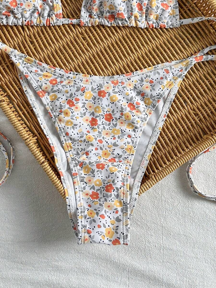 Women's black two-piece bikini set featuring a halter neck with a colorful sun pendant, triangle cups, and high-cut tie-side bottoms.