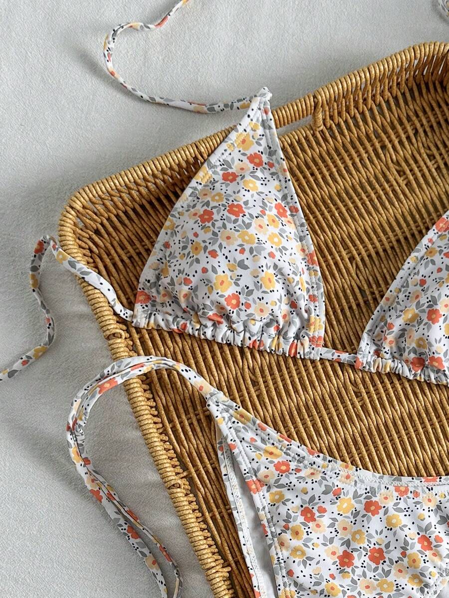 Women's black two-piece bikini set featuring a halter neck with a colorful sun pendant, triangle cups, and high-cut tie-side bottoms.