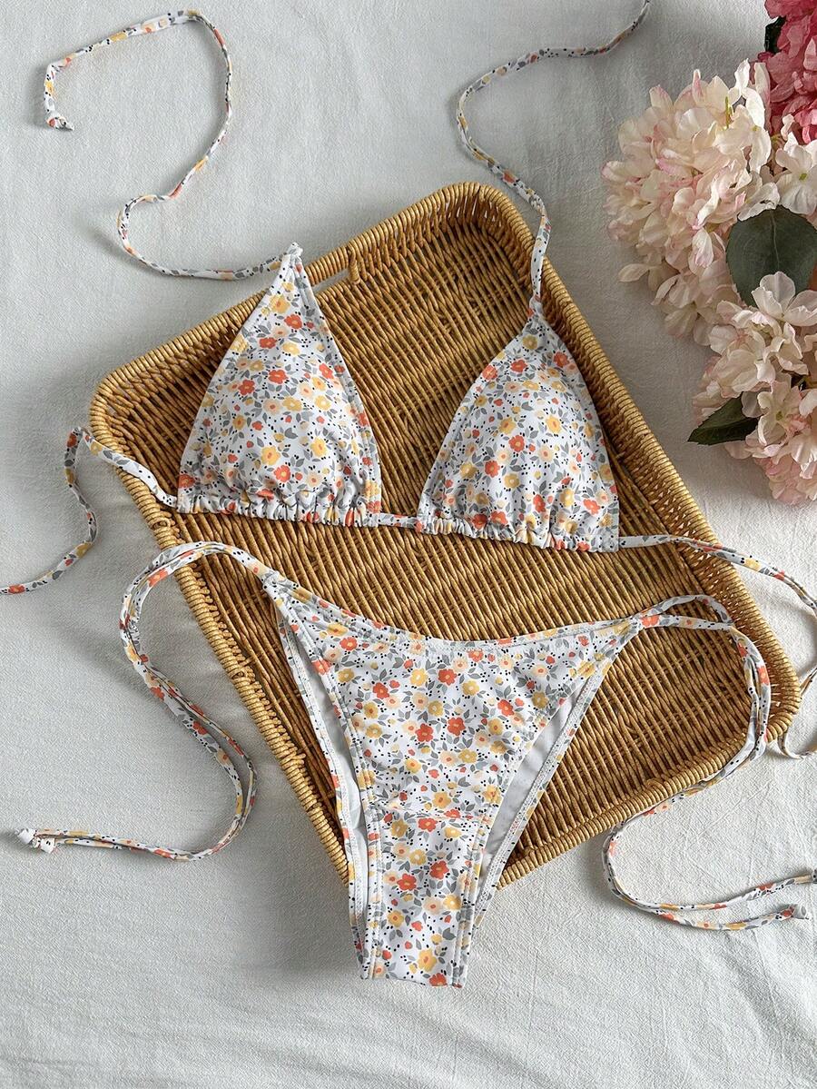 Women's black two-piece bikini set featuring a halter neck with a colorful sun pendant, triangle cups, and high-cut tie-side bottoms.