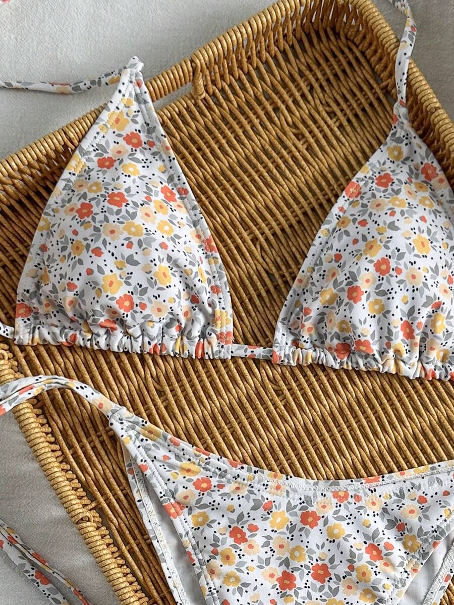 Women's black two-piece bikini set featuring a halter neck with a colorful sun pendant, triangle cups, and high-cut tie-side bottoms.