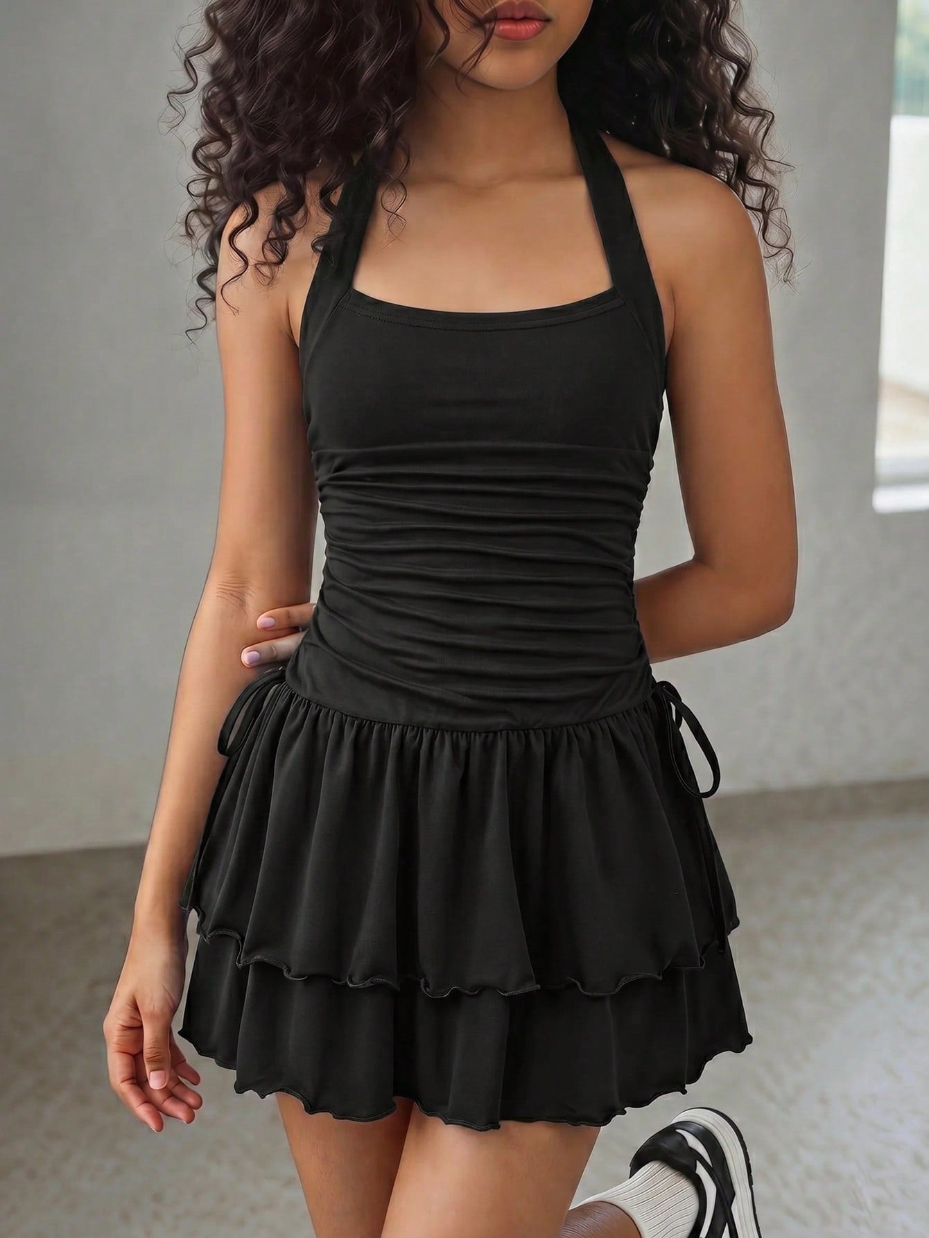 Black sleeveless halter polka dot mini dress for tween girls featuring a high waist and flared hem