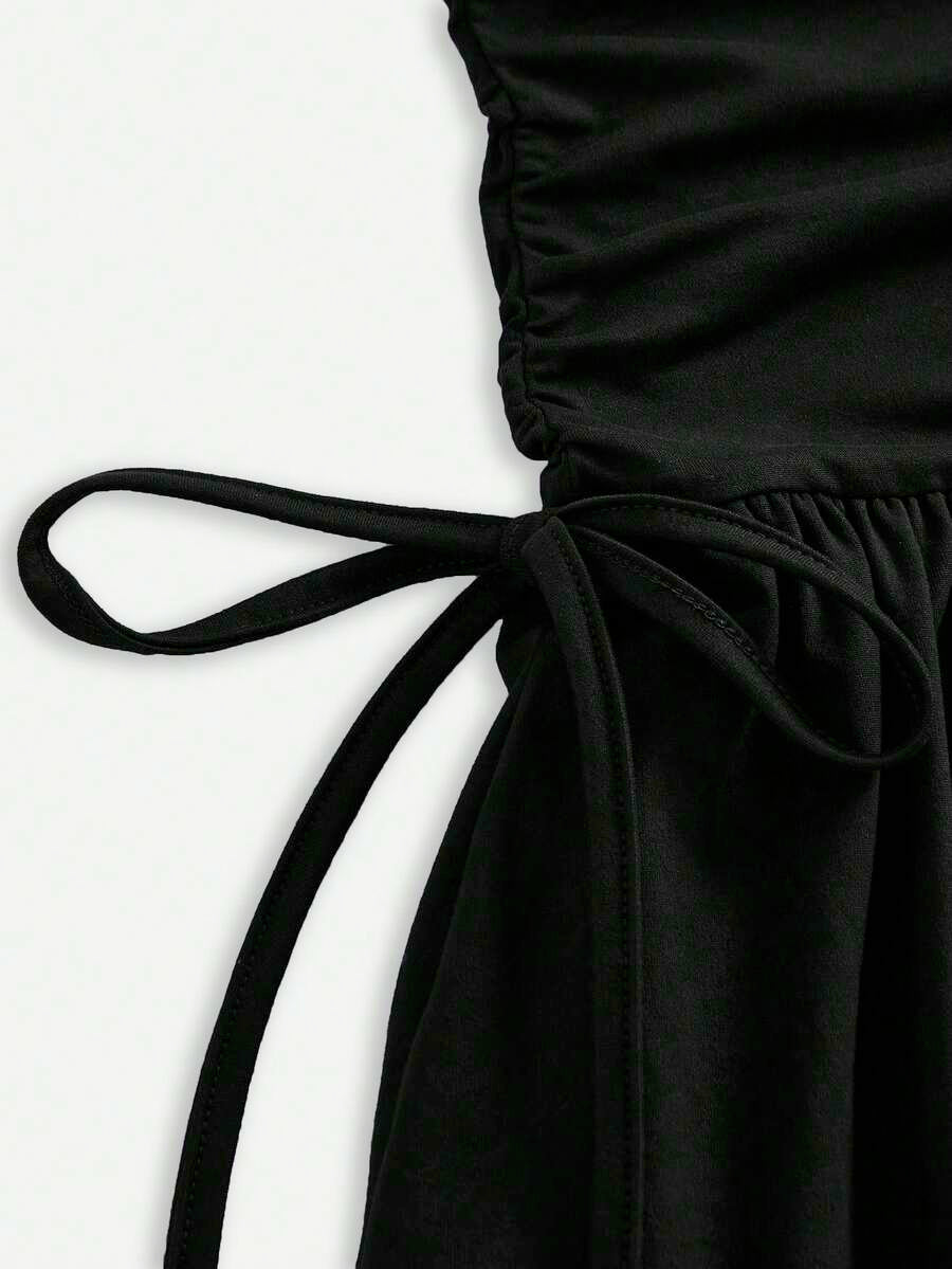 Black sleeveless halter polka dot mini dress for tween girls featuring a high waist and flared hem