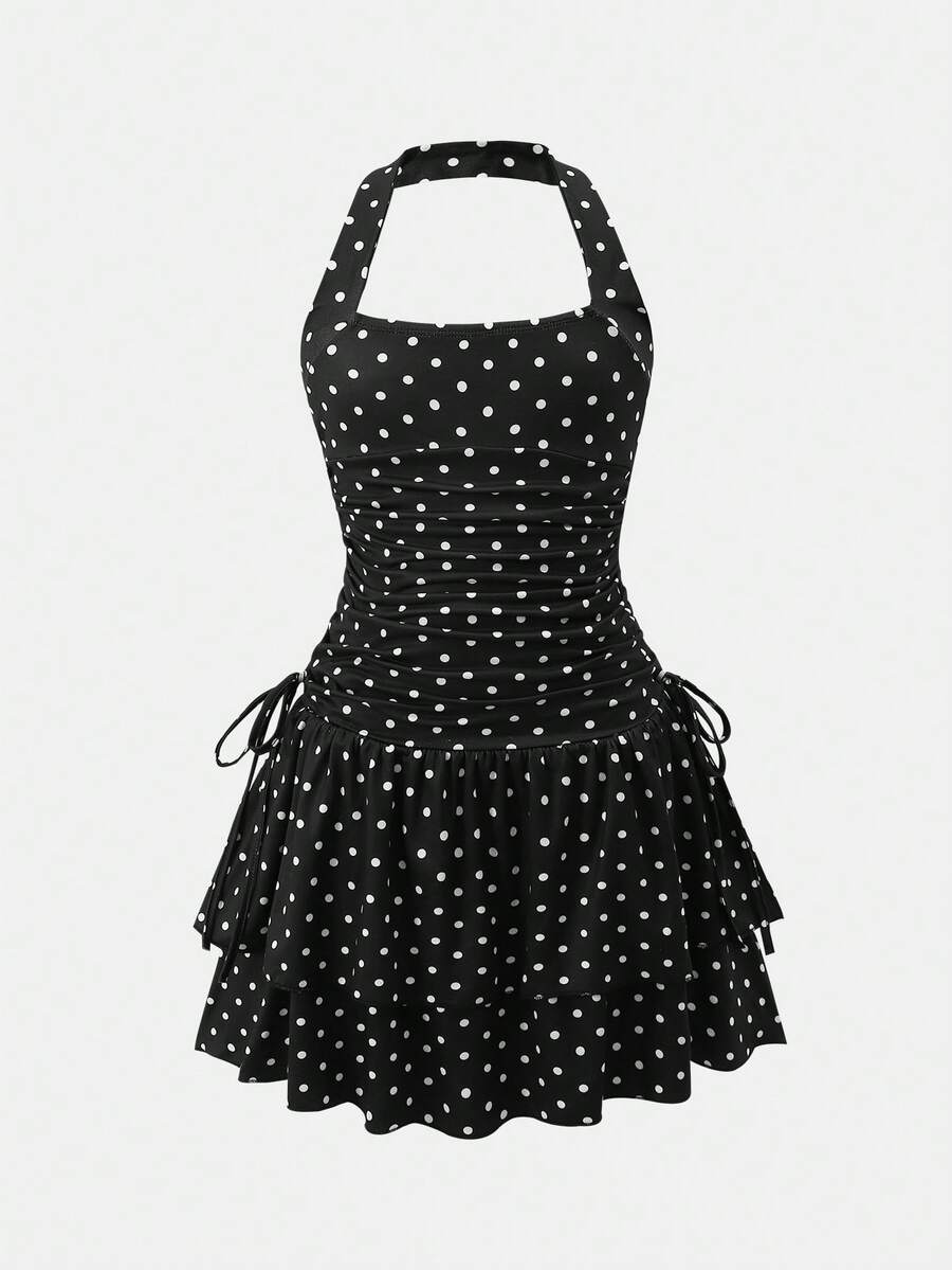 Tween girl wearing a black and white polka dot tiered cami dress with shoulder straps, a high waist, and a ruffle layered hem.