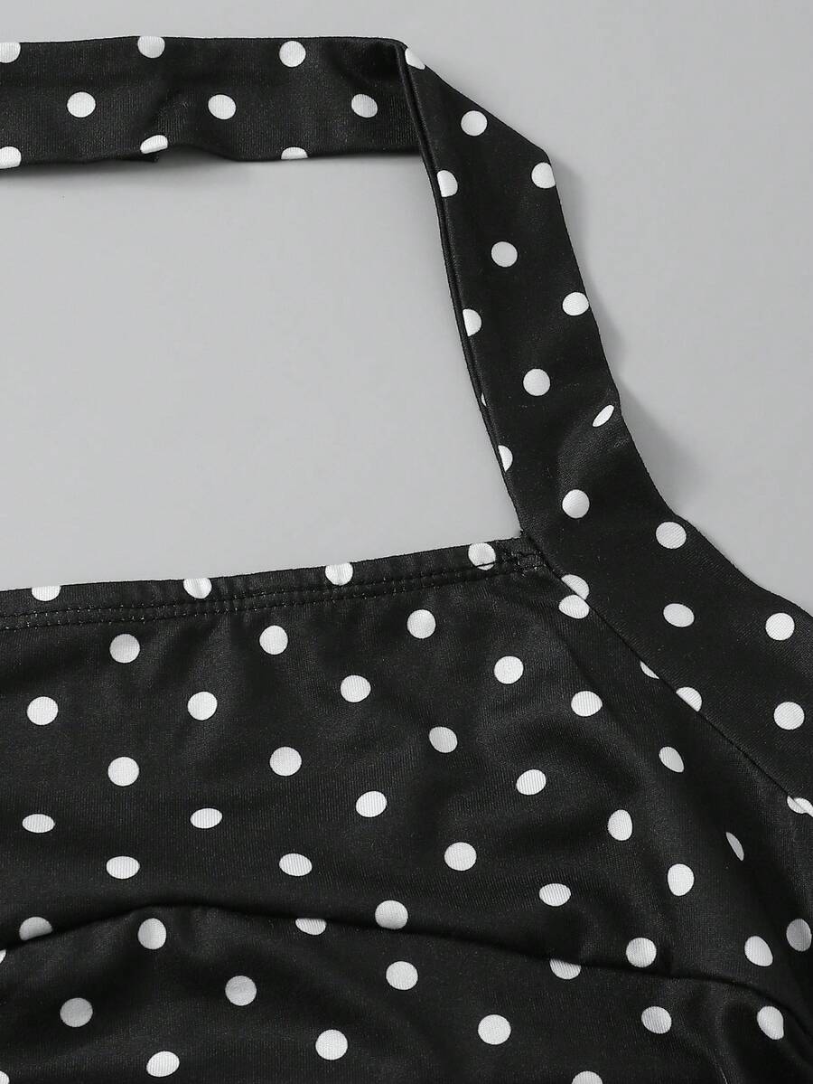 Tween girl wearing a black and white polka dot tiered cami dress with shoulder straps, a high waist, and a ruffle layered hem.