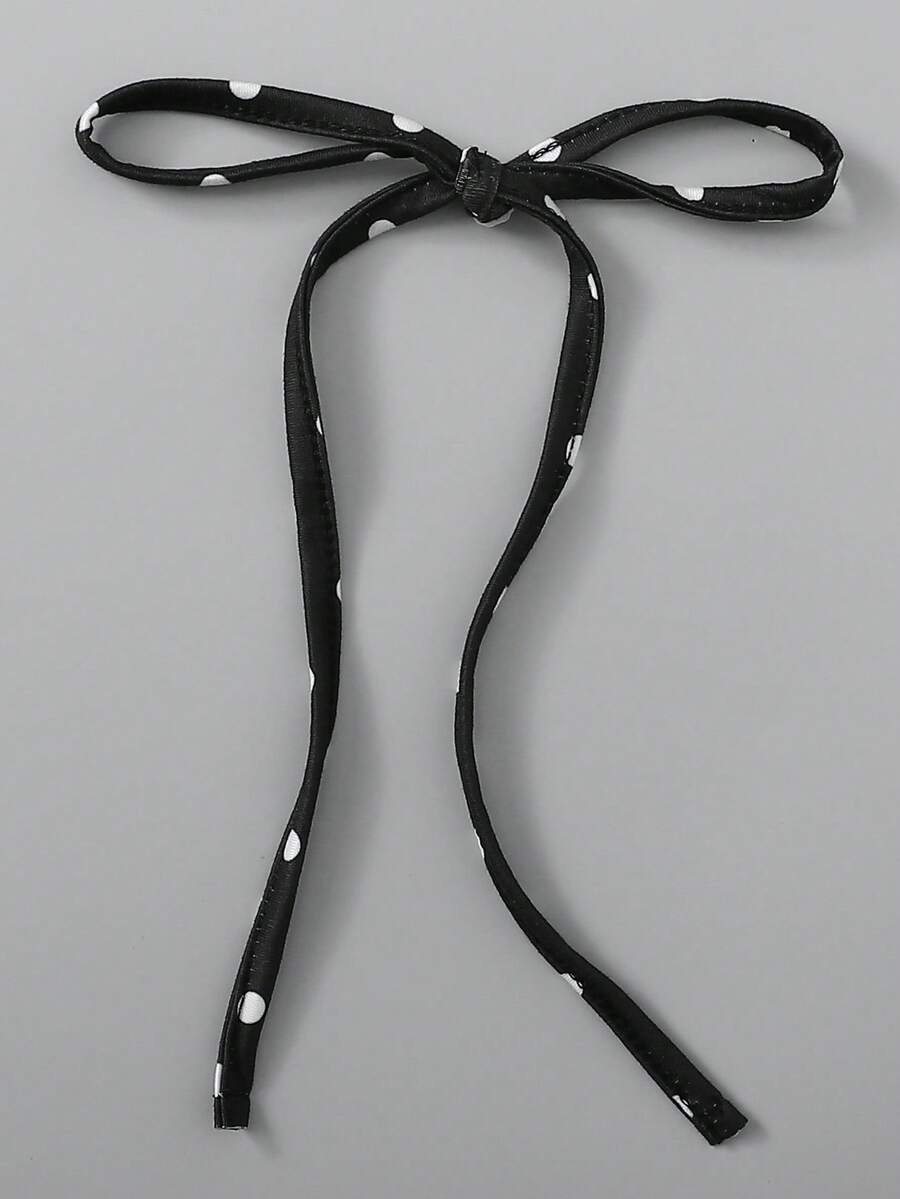 Tween girl wearing a black and white polka dot tiered cami dress with shoulder straps, a high waist, and a ruffle layered hem.