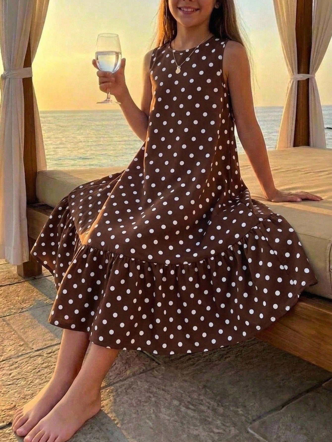 Tween girl wearing a sleeveless black tunic dress featuring a round neck, contrast lace details, and a straight hem.