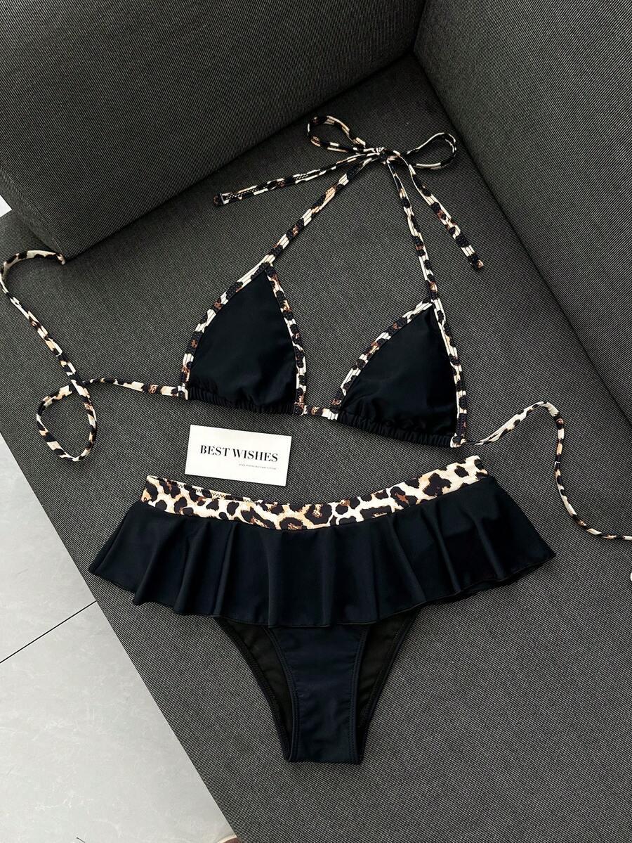 Women's 70s retro black and white polka dot bikini set featuring a halter triangle top and ultra low waist bottoms.