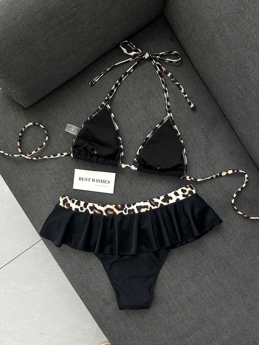 Women's 70s retro black and white polka dot bikini set featuring a halter triangle top and ultra low waist bottoms.