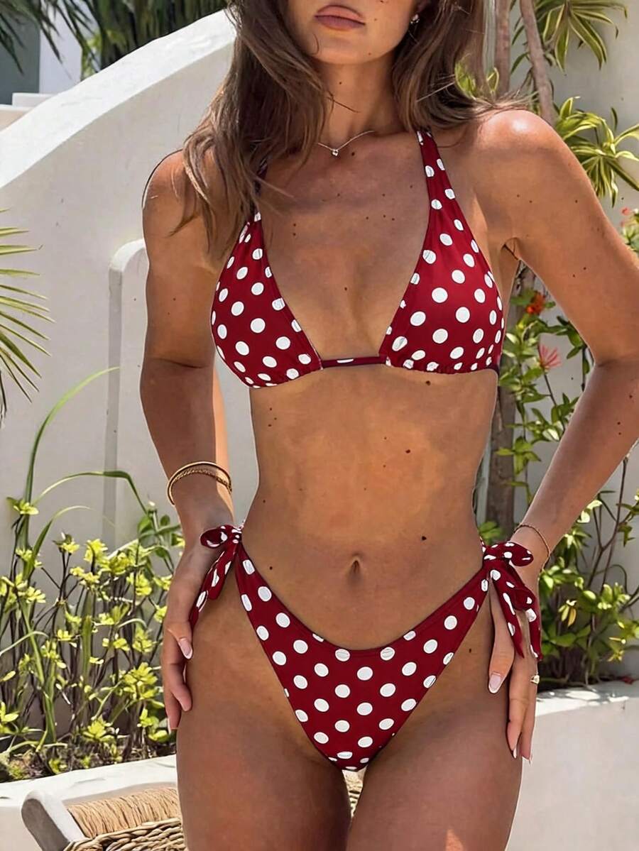 Women's polka dot two-piece bikini set featuring a backless halter top with triangle cups and matching tie-side bottoms.