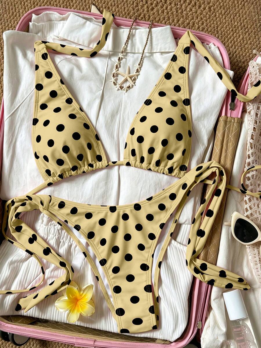 Women's polka dot two-piece bikini set featuring a backless halter top with triangle cups and matching tie-side bottoms.