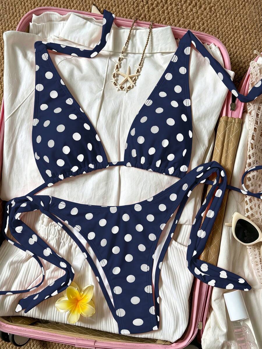 Women's polka dot two-piece bikini set featuring a backless halter top with triangle cups and matching tie-side bottoms.