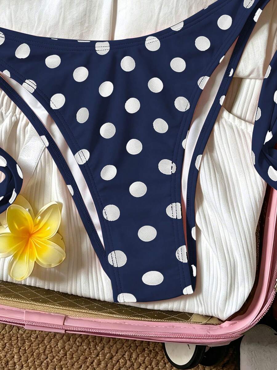 Women's polka dot two-piece bikini set featuring a backless halter top with triangle cups and matching tie-side bottoms.