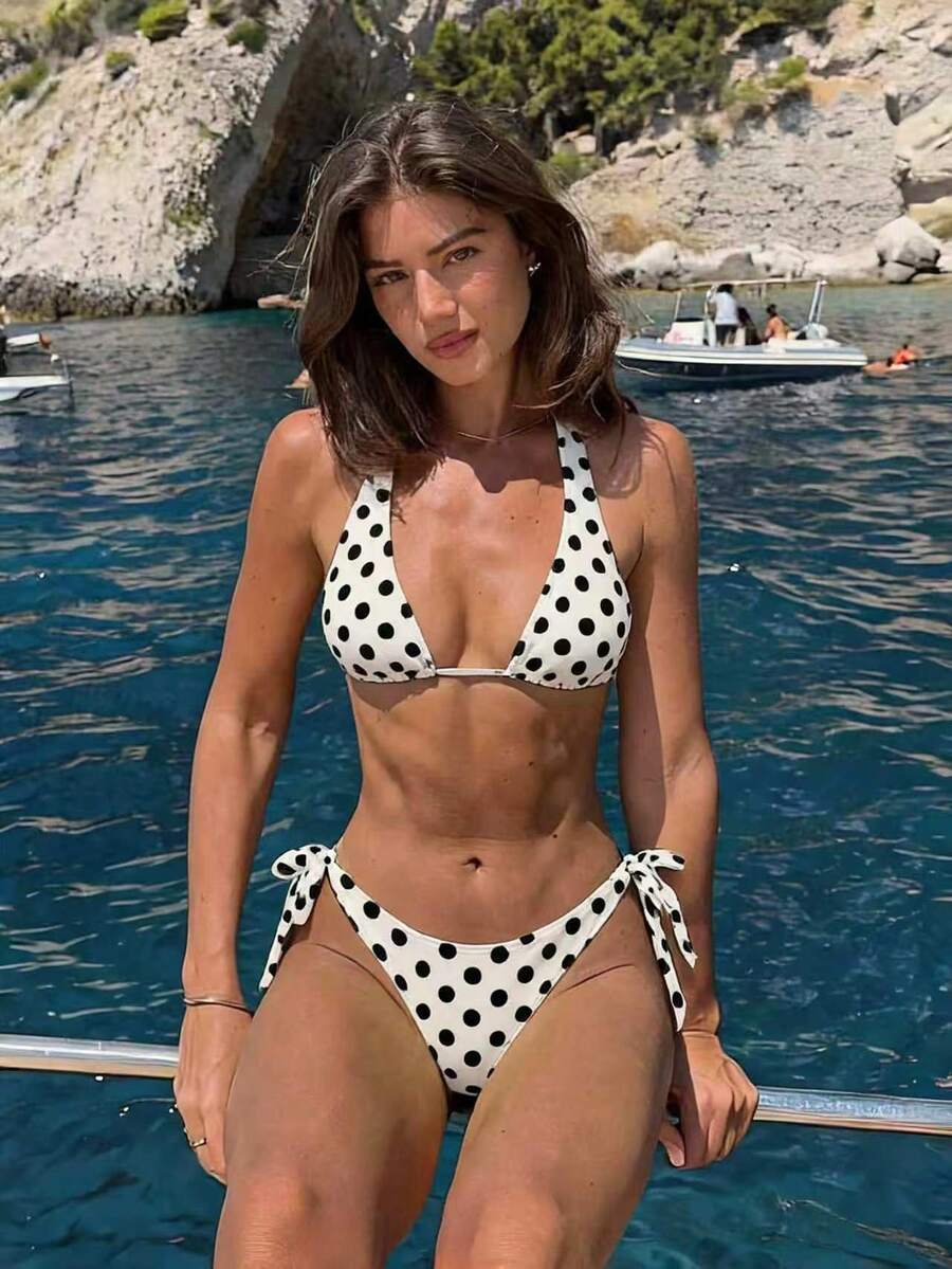 Women's polka dot two-piece bikini set featuring a backless halter top with triangle cups and matching tie-side bottoms.