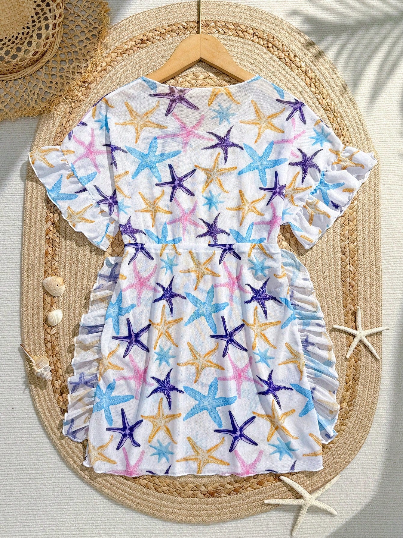 Blue tween girls swimsuit cover up with geometric starfish print, ruffle trim, round neck, short sleeves, and semi-sheer knit fabric for beach or pool wear.