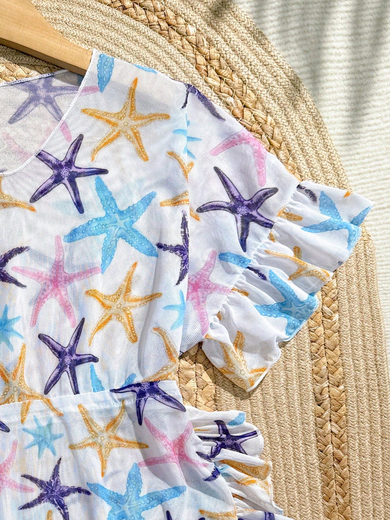 Blue tween girls swimsuit cover up with geometric starfish print, ruffle trim, round neck, short sleeves, and semi-sheer knit fabric for beach or pool wear.