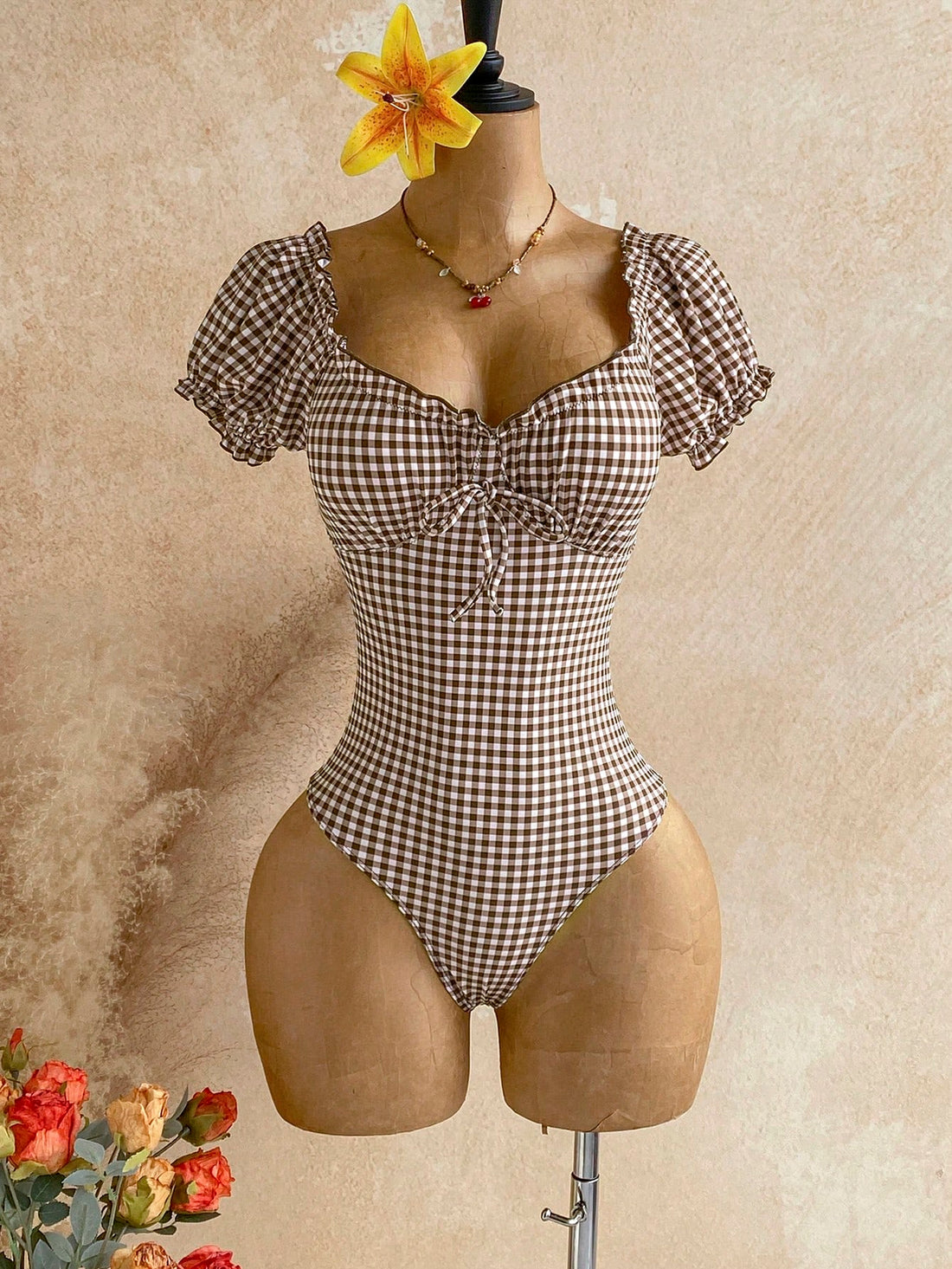 Multicolor plaid one-piece swimsuit for women featuring a sweetheart neckline, front twist detail, short sleeves, and removable padding.