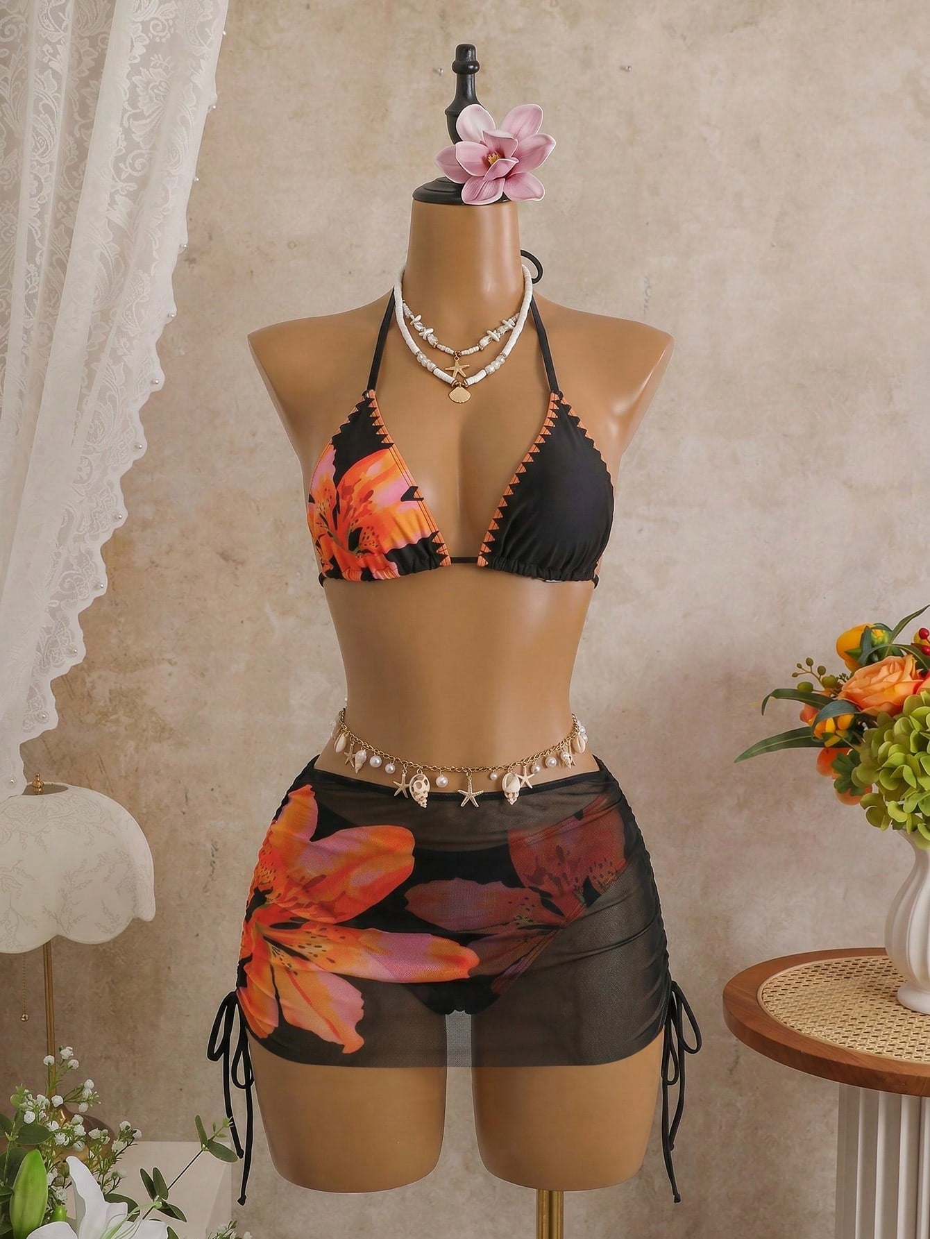 Women's black 3-piece bikini set featuring a halter triangle top with removable padding, high-waisted bottoms, and a knee-length mesh skirt with tie details.