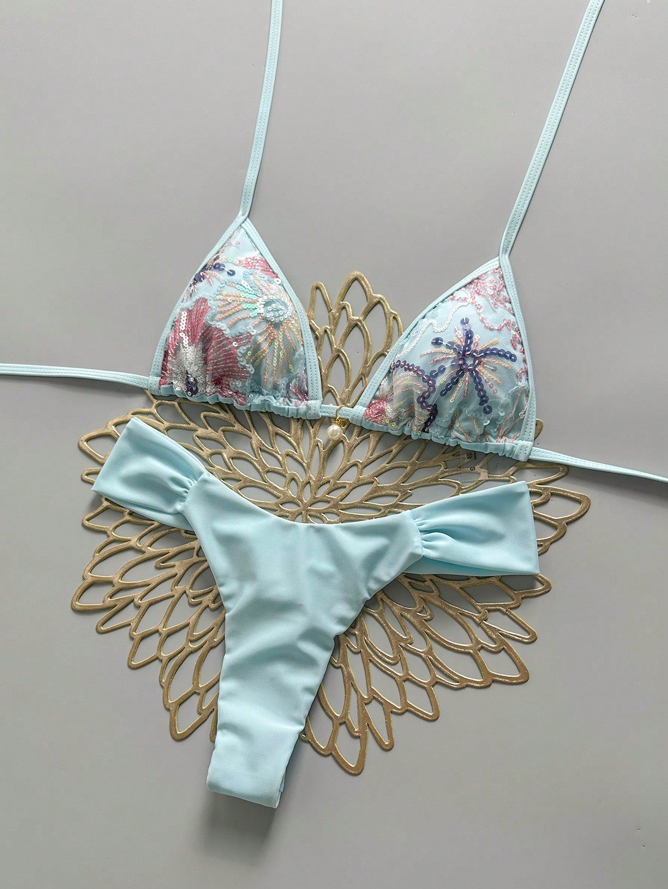 Women's 2-piece triangle cup bikini set in solid color featuring woven pearl shell decoration, halter neckline, and high-waist side-tie ruched bottoms.
