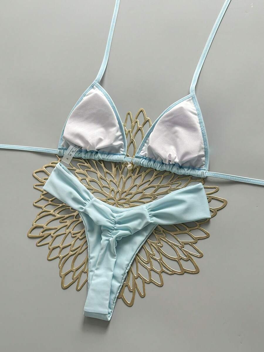 Women's 2-piece triangle cup bikini set in solid color featuring woven pearl shell decoration, halter neckline, and high-waist side-tie ruched bottoms.