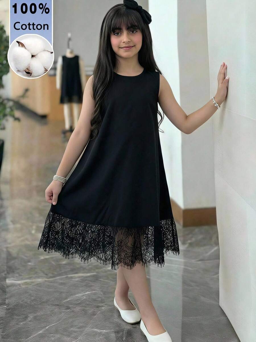 Tween girl wearing a sleeveless black tunic dress featuring a round neck, contrast lace details, and a straight hem.