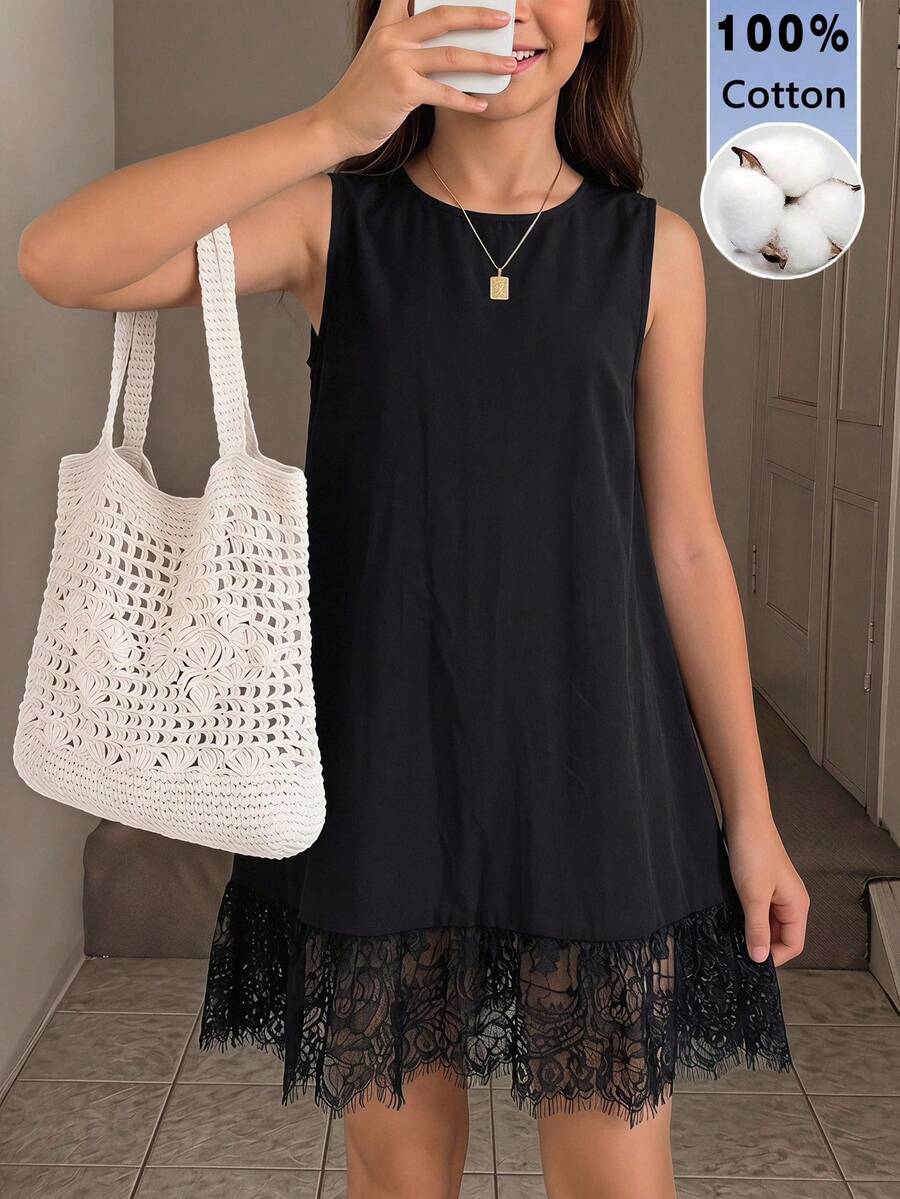 Tween girl wearing a sleeveless black tunic dress featuring a round neck, contrast lace details, and a straight hem.