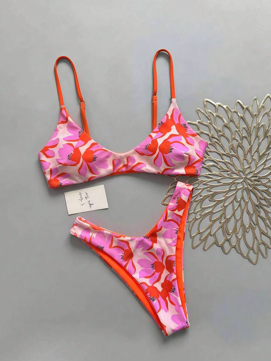 Women's pinkish orange floral print 2-piece bikini set featuring a backless wireless top with spaghetti straps and matching mid-waist bikini bottoms.