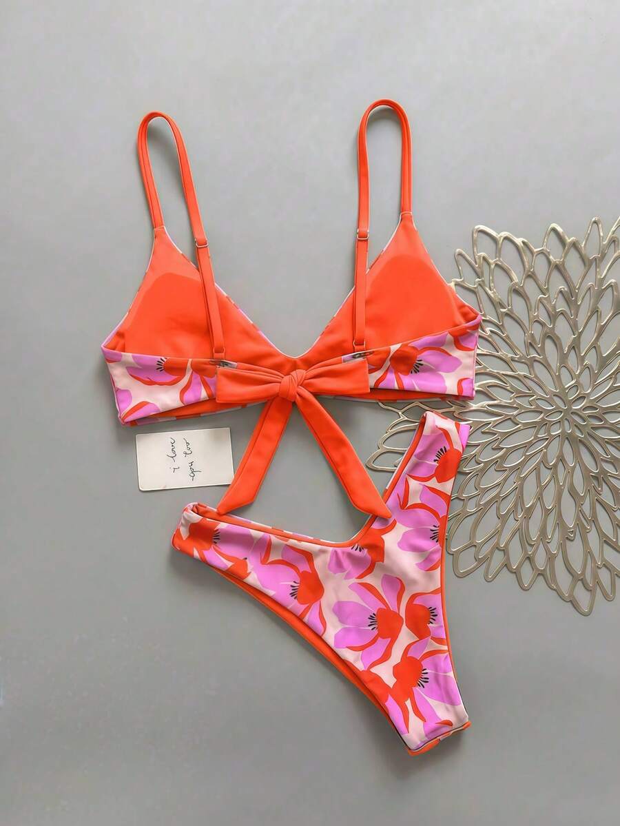 Women's pinkish orange floral print 2-piece bikini set featuring a backless wireless top with spaghetti straps and matching mid-waist bikini bottoms.