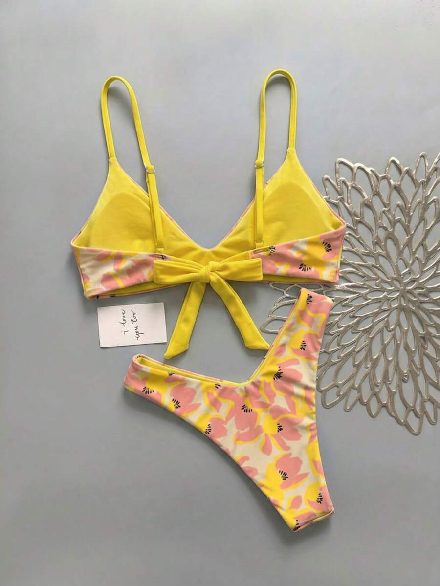 Women's pinkish orange floral print 2-piece bikini set featuring a backless wireless top with spaghetti straps and matching mid-waist bikini bottoms.