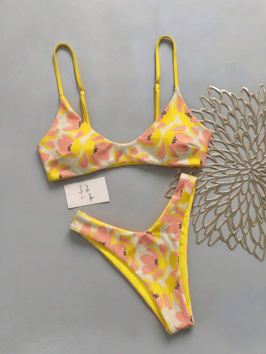Women's pinkish orange floral print 2-piece bikini set featuring a backless wireless top with spaghetti straps and matching mid-waist bikini bottoms.