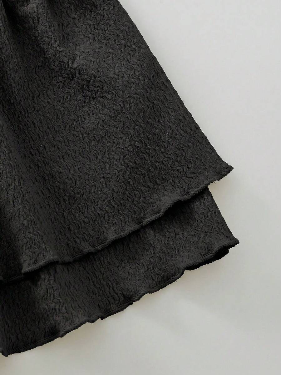 Tween girl black mini dress with halter neckline, backless design, tiered layer detail, high waist, flounce hem, and sleeveless slim fit.