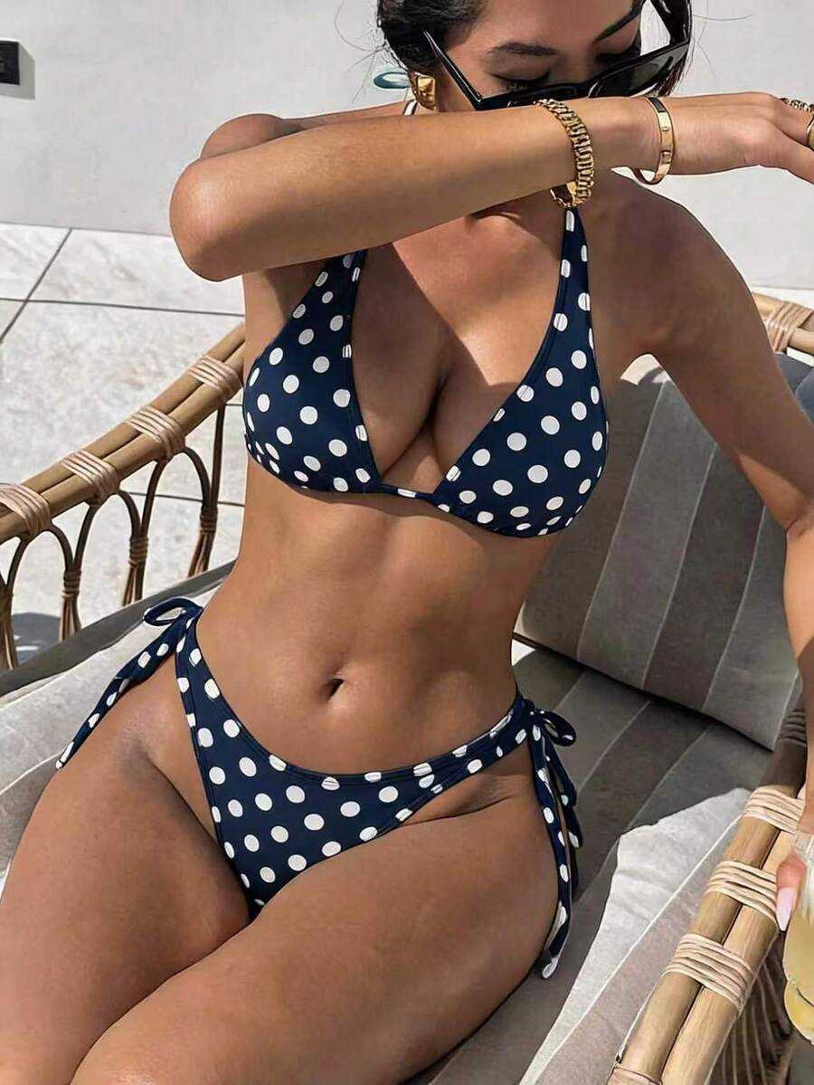 Women's polka dot two-piece bikini set featuring a backless halter top with triangle cups and matching tie-side bottoms.