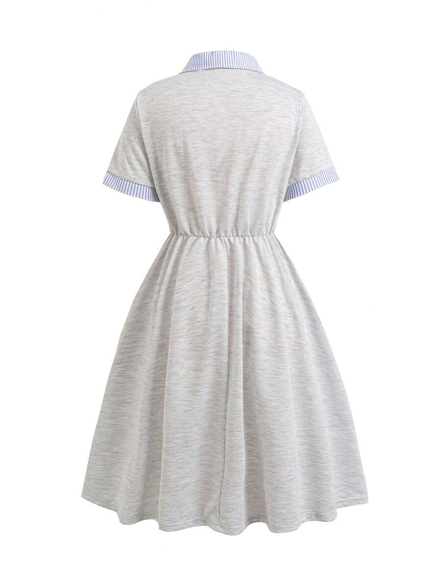 Tween girl wearing an apricot short sleeve A-line dress featuring a round neck, high waist with a belt, and flared hem.