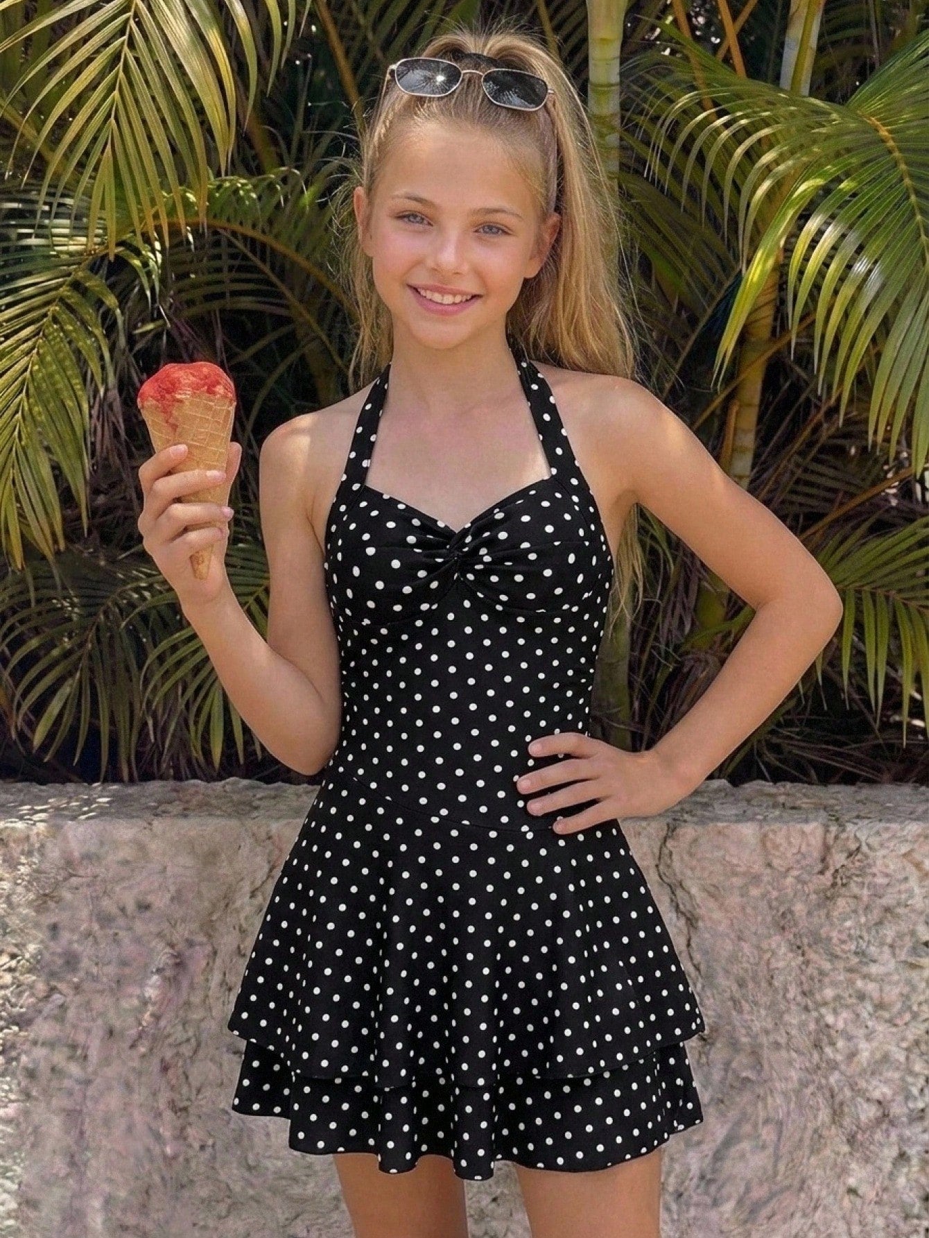 Black sleeveless halter polka dot mini dress for tween girls featuring a high waist and flared hem