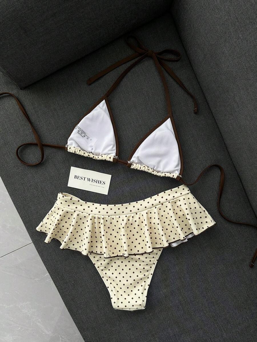Women's 70s retro black and white polka dot bikini set featuring a halter triangle top and ultra low waist bottoms.