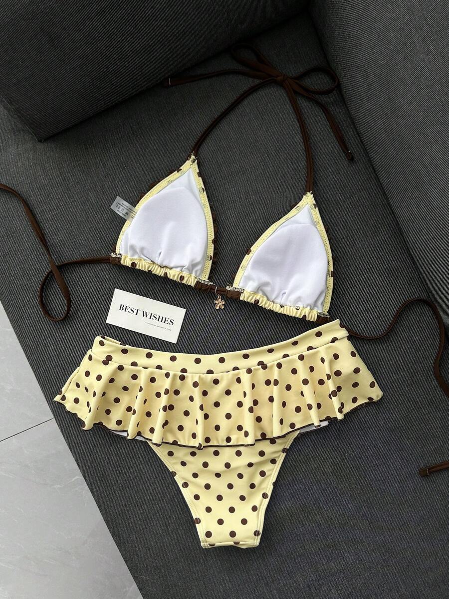 Women's 70s retro black and white polka dot bikini set featuring a halter triangle top and ultra low waist bottoms.