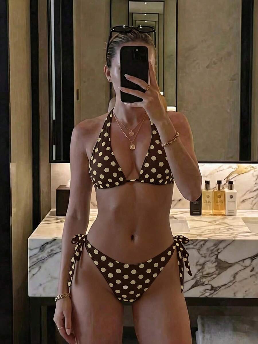 Women's polka dot two-piece bikini set featuring a backless halter top with triangle cups and matching tie-side bottoms.