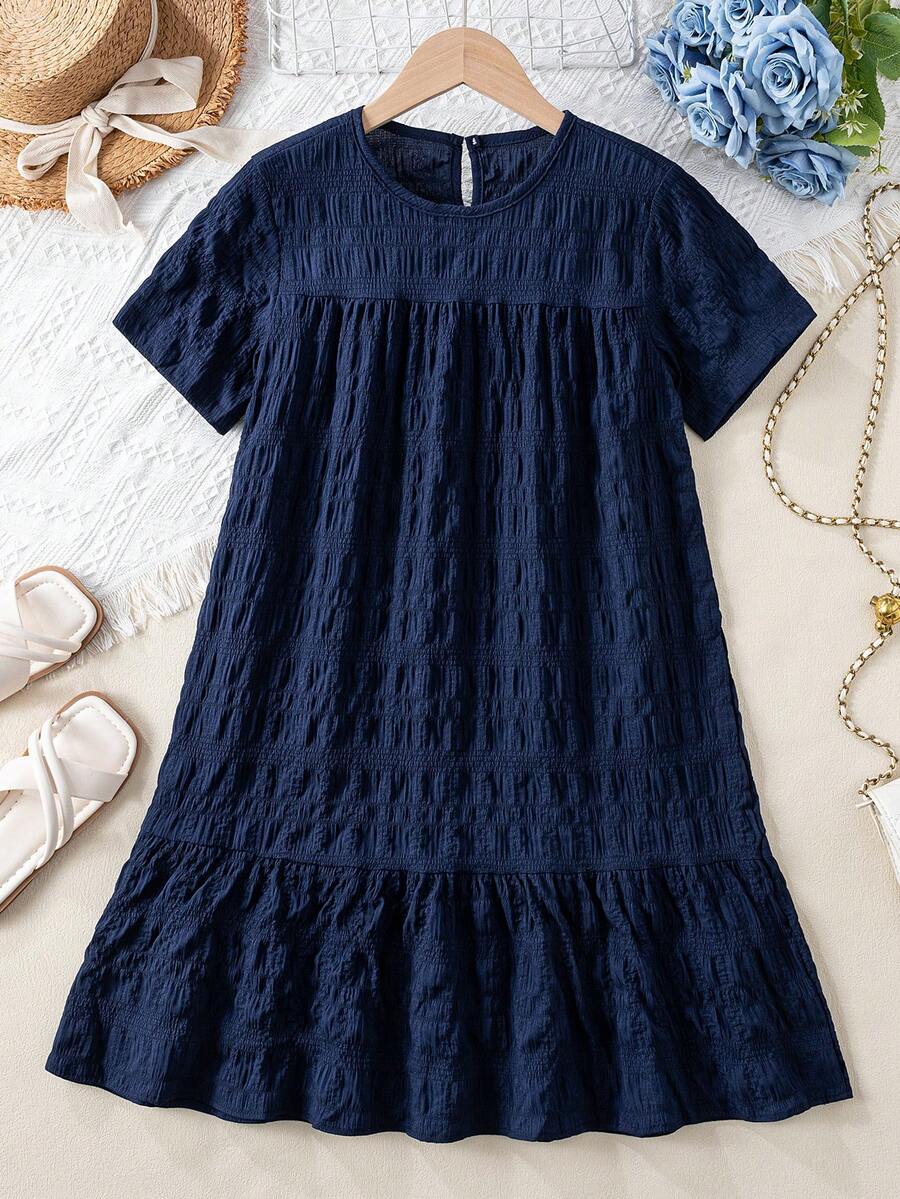 Tween girl wearing an Army Green textured short sleeve smock midi dress with round neck and ruffle flounce hem.