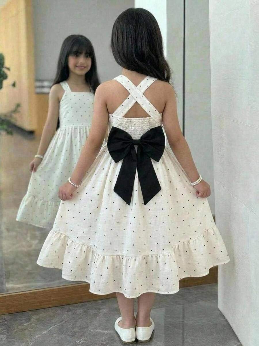 Pink sleeveless tween girls vacation dress with all-over fruit and vegetable print, strap neckline, belted high waist, cut-out detail, and flared ruffle hem.