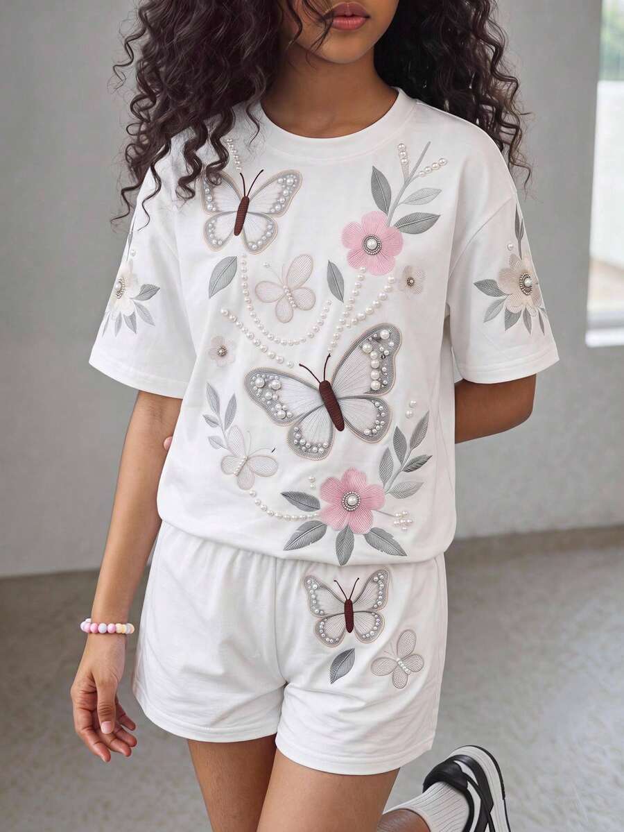 Tween girl wearing a black and white striped drop-shoulder crew neck t-shirt with bow embroidery paired with matching tie-waist shorts.