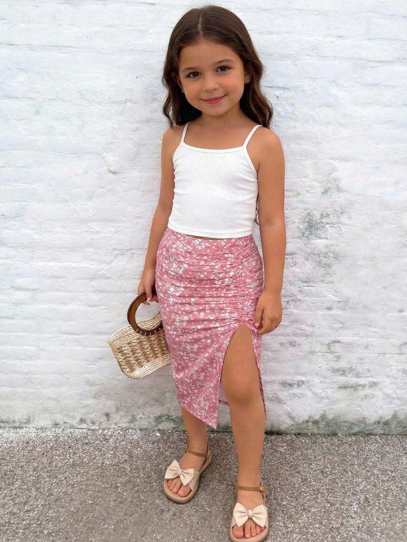 Tween girl wearing a 2-piece set featuring a black rib-knit spaghetti strap camisole top and a ruched leopard print midi skirt.