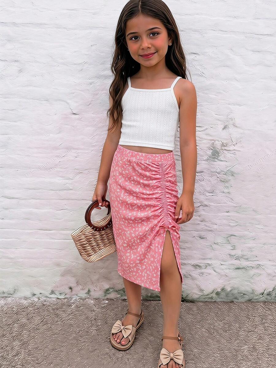Tween girl wearing a 2-piece set featuring a black rib-knit spaghetti strap camisole top and a ruched leopard print midi skirt.