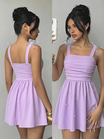 Tween girl wearing a purple sleeveless striped cami mini dress featuring a high waist flared hem and beaded pearl details.