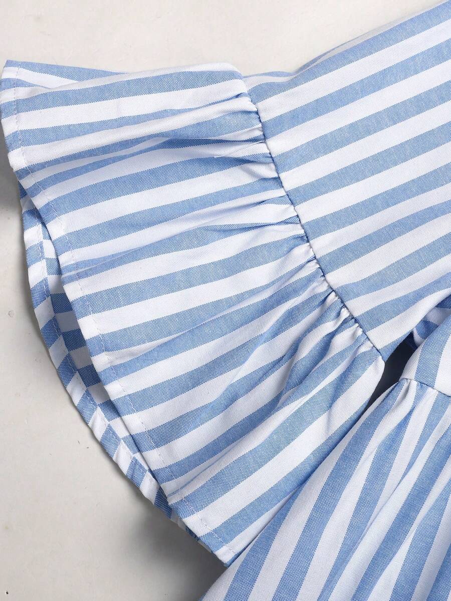 Tween girl wearing a black striped smock shirt dress with flounce half sleeves, a stand collar, and a ruffled hem.