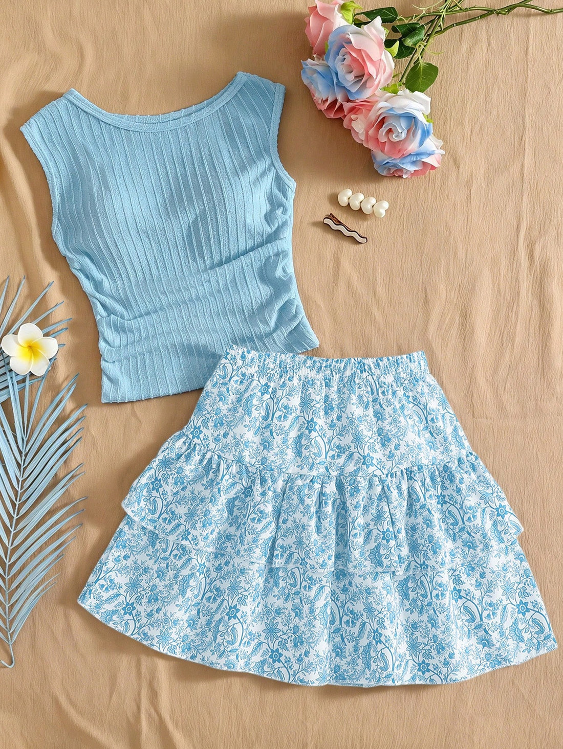 Light blue two-piece outfit set for tween girls with a sleeveless round neck vest top and a tiered ruffle cake skirt featuring a plant pattern.